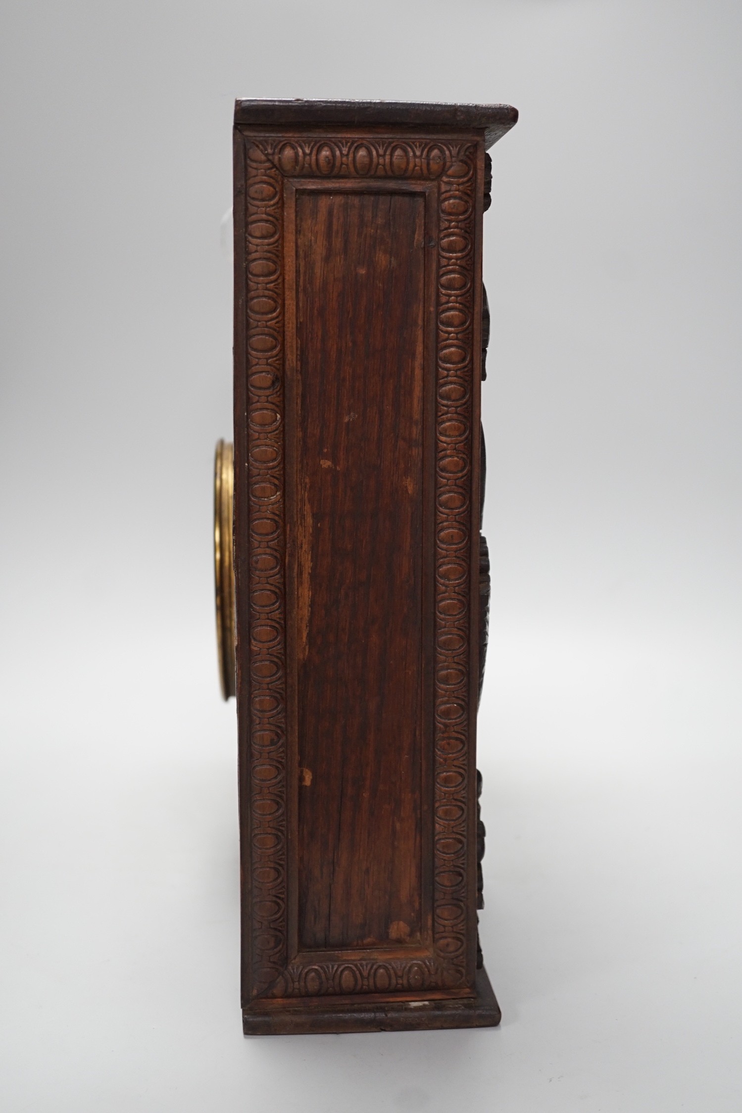 A late 19th century / early 20th century folk art carved oak cased clock, decorated with hanging dead game amongst oak sprigs and acorns, 34x39cm